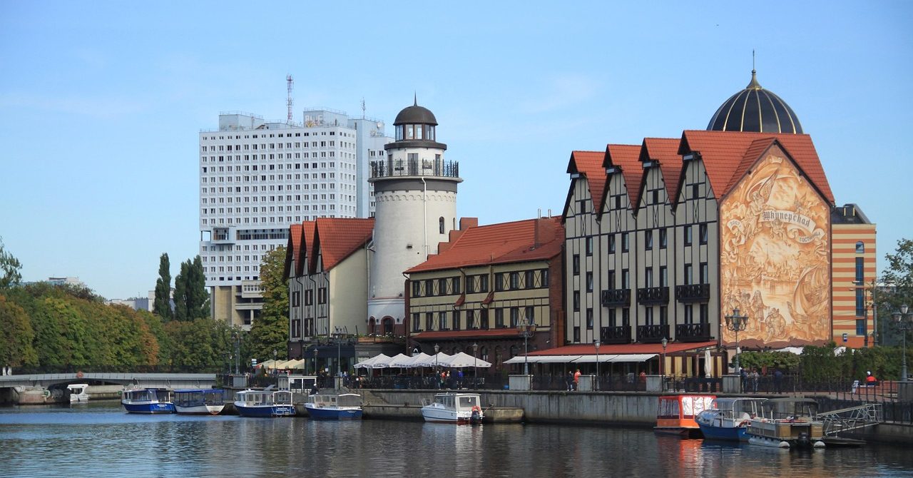 Waterfront view of Kaliningrad’s Fishing Village with traditional-style buildings and a lighthouse.