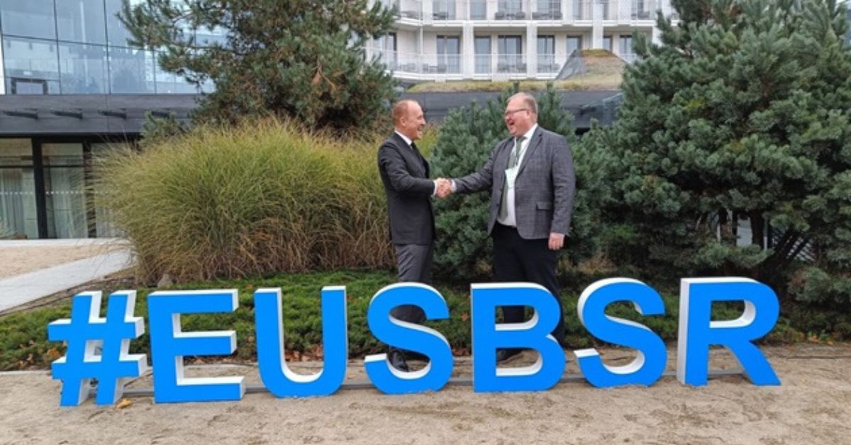 Representatives of the Norwegian and Estonian Foreign Ministries shaking hands in front of EUSBSR sign at the Annual Forum in Sopot, Poland.