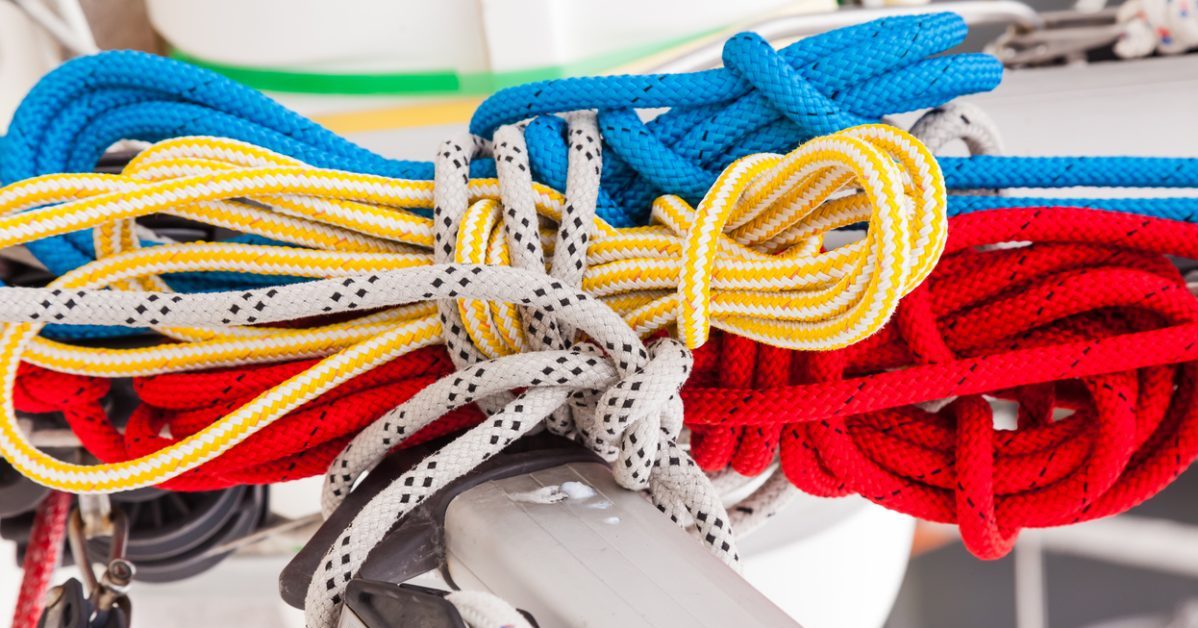 Spare multi-colored ropes tied to the mast of a sailing ship, close-up. One rope is fixed on the fixing rollers on the sailboat mast.