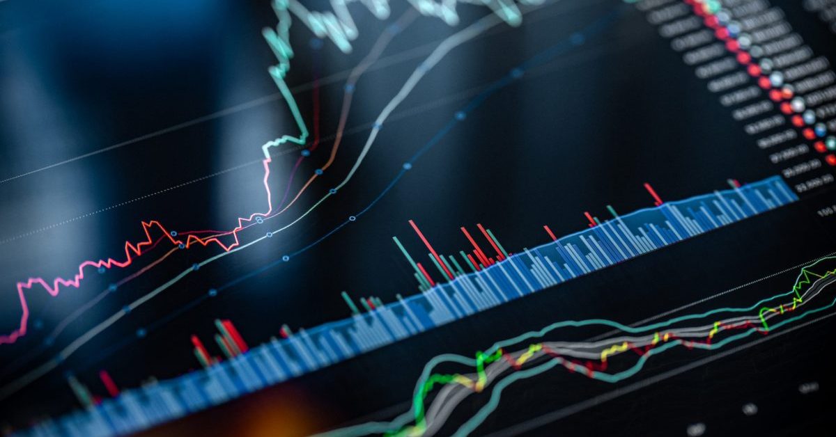 A close-up view of a digital financial chart displaying multiple fluctuating line graphs and bar indicators on a dark background, suggesting stock market or data analysis trends.