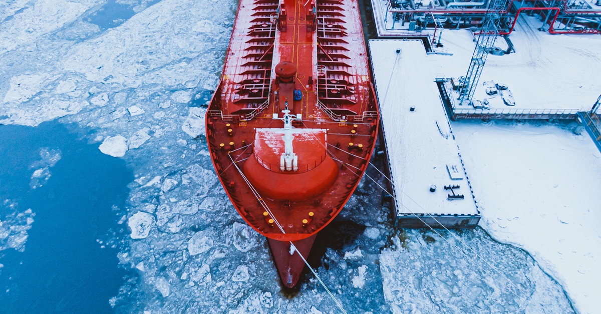 Oil shipment on big red tanker from terminal pumping system on water covered with thick layer of broken ice in frosty winter aerial view