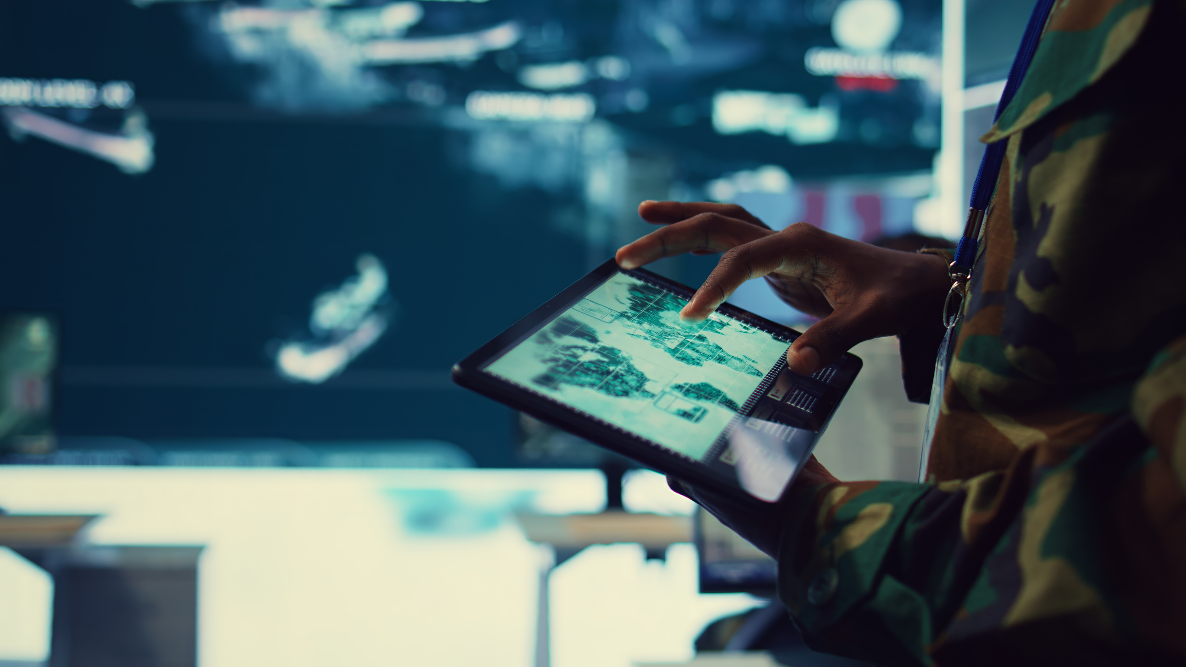 Army soldier reviews targets on a satellite world map to ensure global protection, works on tablet in military command center.