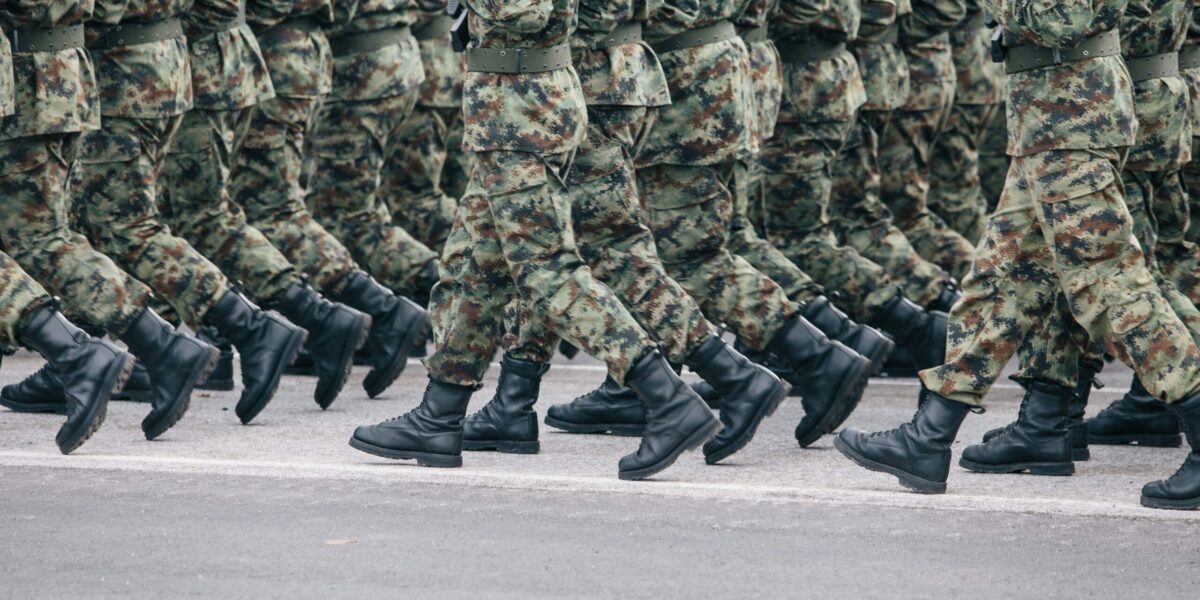 Soldiers dressed in army camouflage march in formation.